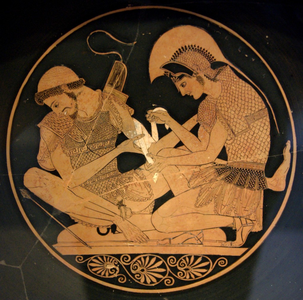 Two ancient Greek warriors are depicted; one bandages the other's arm. They are seated and wearing armor, surrounded by a decorative border with floral patterns on pottery. No text is present.